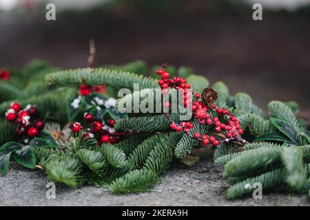 Macro foto della vasca calda in ghisa fumante con idromassaggio in inverno con neve e candele decorate. Rametti di Natale con rosa guelder e coni di pino Foto Stock