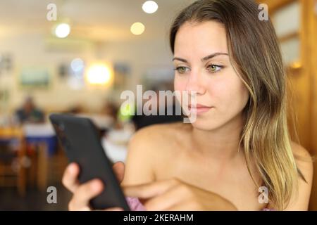 Teenager che usa uno smartphone seduto al ristorante Foto Stock