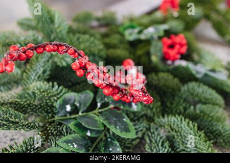 Macro foto della vasca calda in ghisa fumante con idromassaggio in inverno con neve e candele decorate. Rametti di Natale con rosa guelder e coni di pino Foto Stock