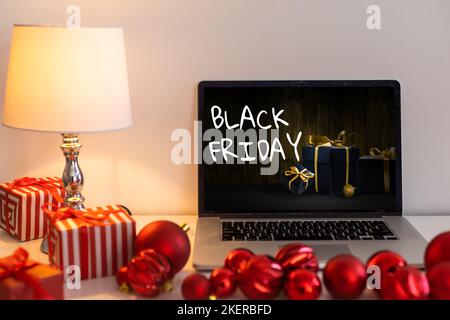 Concetto di shopping del Black Friday scritto sullo schermo nero del notebook contro lo sfondo sfocato delle luci di natale Foto Stock