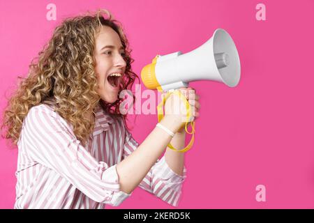 La giovane donna grida in un megafono. Sfondo rosa isolato. Persone emozioni sincere stile di vita concetto. Foto Stock