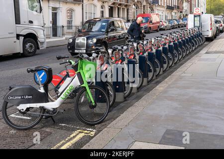 Uber + Lime e Santander hanno sponsorizzato il noleggio di biciclette elettriche a Londra. Un ciclista che picking una bicicletta come un taxi passa. Inghilterra Foto Stock