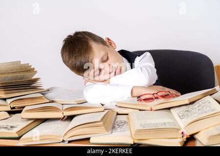 Concetto di istruzione. Lo studente si stancò facendo i compiti a casa e si addormentò sui libri. Foto Stock