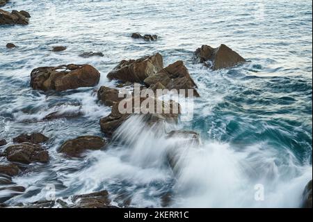 Onde che si rompono sulle rocce con immagine a lunga esposizione Foto Stock