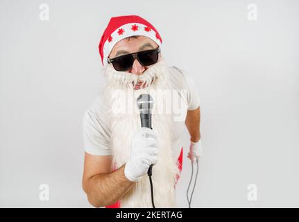 Vacanze e Natale concetto. Babbo Natale canta con un microfono in mano. Isolato su bianco Foto Stock