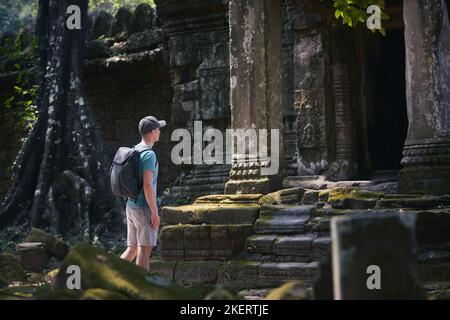 Uomo con zaino che arriva al tempio antico. Viaggiatore in Cambogia. Foto Stock