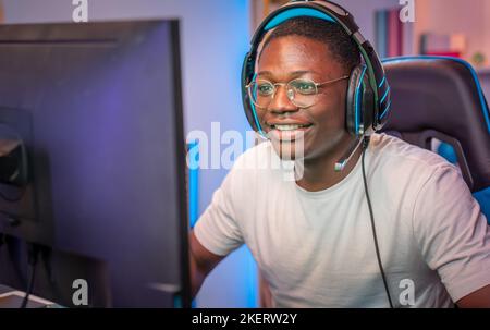 Uomo afroamericano che gioca i video giochi d'azione sul flusso di computer in diretta di radiodiffusione. Foto Stock