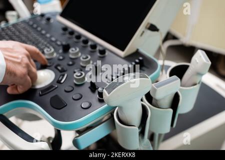 vista parziale del medico utilizzando il pannello di controllo della macchina a ultrasuoni in ospedale, immagine stock Foto Stock