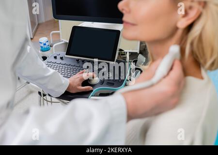 vista parziale del medico che esamina la donna offuscata mentre utilizza la macchina ecografica,immagine di scorta Foto Stock