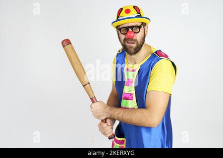 Concetto di vacanza. Il clown è un uomo in un vestito blu e giallo brillante con una mazza da baseball. Foto Stock