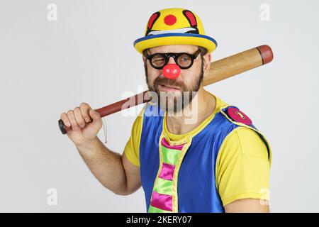 Concetto di vacanza. Il clown è un uomo in un vestito blu e giallo brillante con una mazza da baseball. Foto Stock
