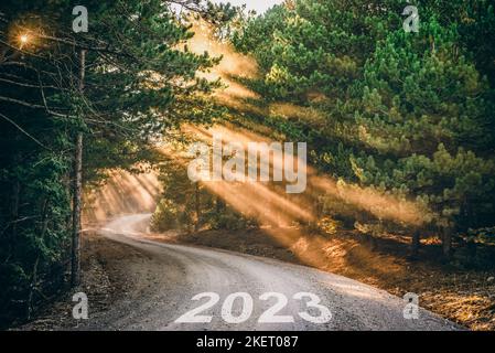2023 scritto su strada forestale al tramonto. Concetto per il nuovo anno 2023. Foto Stock