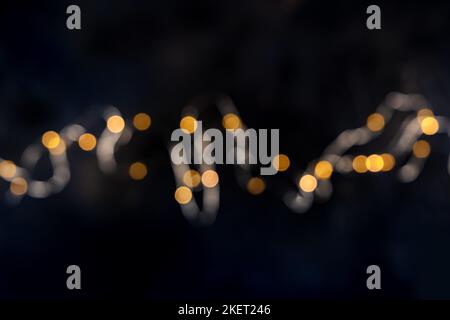 Luci delle fate, ghirlanda di cordicelle, sfocate, scattate dall'alto con bokeh su sfondo nero. Banner festivo astratto con spazio copia Foto Stock