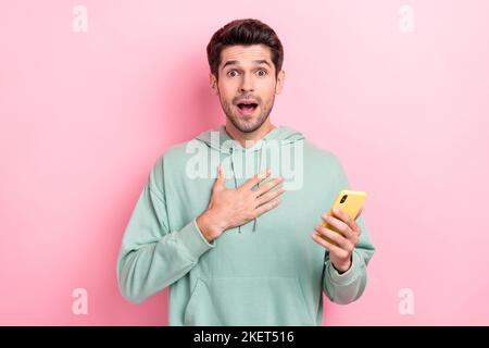 Foto di giovane divertente impressionato imprevisto uomo stordente influencer scioccato toccare petto ecommerce grande profitto tenere telefono isolato su sfondo di colore rosa Foto Stock