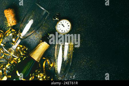 Felice Anno Nuovo. Bottiglia di champagne con due bicchieri, streamer dorati, glitter scintillante e orologio antico con spazio copia su sfondo grunge. Nuovo Yea Foto Stock