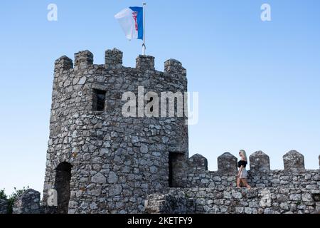 I turisti si arrampicano sulle mura fortificate e torrette del 10th ° secolo Castello moresco dei Mori (Castelo dos Mouros) sopra Sintra, Portogallo. Foto Stock