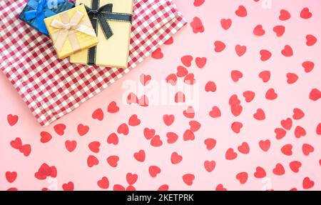 Scatole regalo e sfondo rosa con piccoli cuori, piatto. Foto Stock