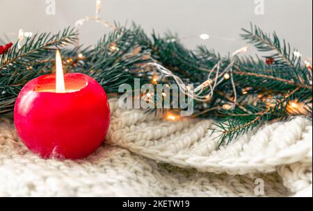 Composizione natalizia con candela, elemento a maglia con rami di abete. Foto Stock