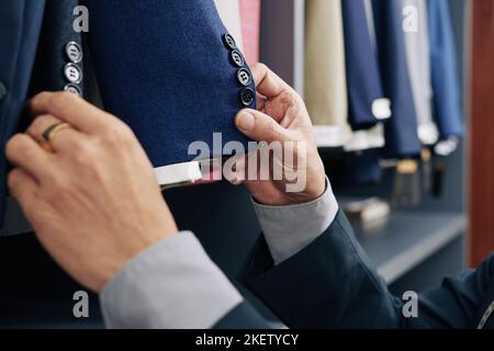 Immagine ravvicinata del cliente che controlla i dettagli della giacca prima di provarla Foto Stock