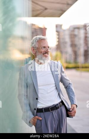 Elegante uomo d'affari anziano felice vestito in piedi all'aperto, ritratto. Foto Stock