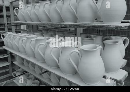 Ripiani con caraffe in ceramica lasciati asciugare prima di sparare. Tinta bianco e nero. Foto Stock