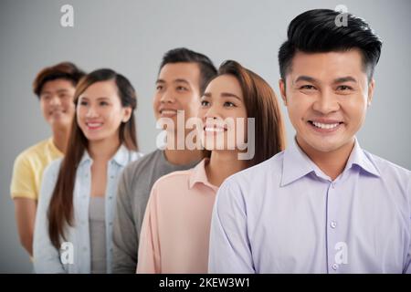 Felice uomo d'affari vietnamita e i suoi colleghi dietro Foto Stock