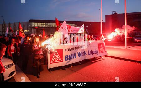 Lipsia, Germania. 14th Nov 2022. I dipendenti BMW lasciano lo stabilimento di Lipsia con bandiere, torce e bengalos per uno sciopero di avvertimento. IG-Metall aveva richiesto lo sciopero di avvertimento durante il terzo round in corso di contrattazione collettiva nell'industria metallurgica ed elettrica. L’Unione sta chiedendo salari e stipendi più alti dell’8 per cento in risposta agli aumenti dei prezzi. Credit: Jan Woitas/dpa/Alamy Live News Foto Stock