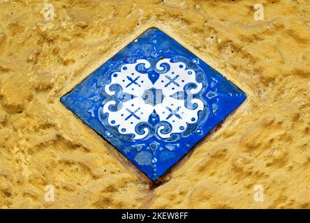 Piastrella blu decorativa su parete gialla Foto Stock