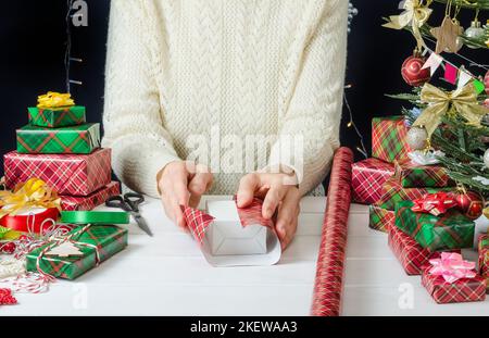 Istruzioni dettagliate per la foto per l'imballaggio di un regalo di Natale, passo 1- il processo di imballaggio di un regalo con carta da imballaggio. Foto Stock