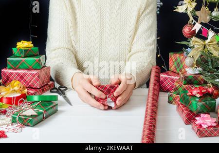 Istruzioni fotografiche passo passo per passo per l'imballaggio di un regalo di Natale, passo 2 - fissaggio della carta da imballaggio con nastro adesivo. Foto Stock