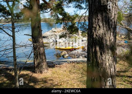 Un solo kayak in riva a un'isola nell'arcipelago di Stoccolma, Svezia. Kayak giallo ancorato su una spiaggia. Foto Stock