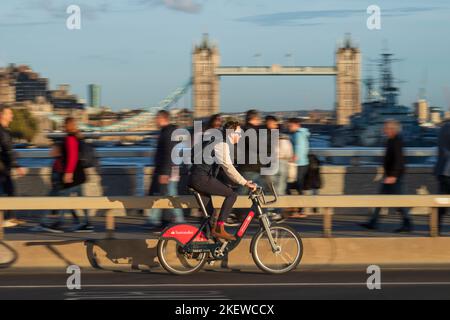 Un uomo che pedalò attraverso il London Bridge durante l'ora di punta, con un trasporto per Londra Santander Cycles noleggio biciclette, comunemente noto come una 'Boris Bike'. Londra Foto Stock