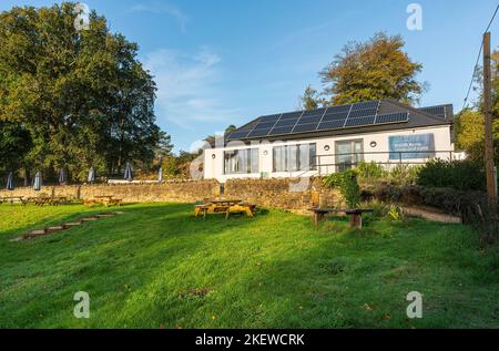 Caffè e negozio di RSPB Arne con giardino, muro di pietra e ombrelloni e tavoli da patio in una mattina di sole blu. Arne, Wareham, Dorset Foto Stock