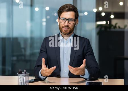 Webcam vista, maturo uomo d'affari ufficio parlare con i colleghi in remoto on-line, uomo che guarda la fotocamera e sorridente, investitore di successo al lavoro in tuta d'affari, executive in occhiali e barba. Foto Stock
