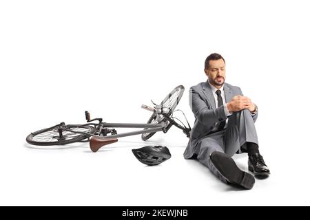 Uomo d'affari che cade da una bicicletta e tiene il ginocchio isolato su sfondo bianco Foto Stock