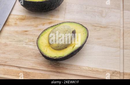 Avocado su tavolo di legno. Avocado in ciotola. Avocado fresco crudo. Foto Stock