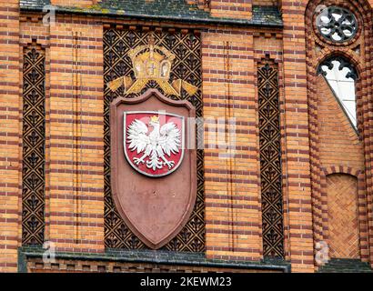 KOSZALIN, POLONIA - 5 AGOSTO 2022: Cresta polacca su un edificio di mattoni rossi nell'ufficio postale di Koszalin Foto Stock