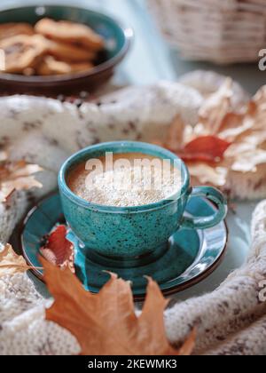 White knitted scarf, blue cup of coffee and dry yellow leaves Stock Photo