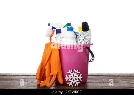 Secchio con prodotti per la pulizia e fiocchi di neve sul tavolo su sfondo bianco Foto Stock