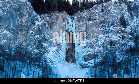 Vista aerea del drone della cascata ghiacciata con un po' d'acqua che scorre. Splendido e magico scenario delle vacanze invernali per gli amanti della natura. Foto Stock