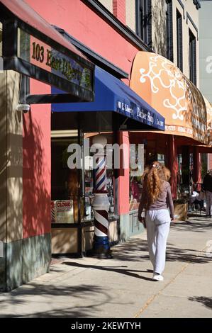 Ann Arbor, Michigan, Stati Uniti. Donna che cammina lungo una strada costeggiata da negozi, ristoranti e aziende vicino al campus dell'Università del Michigan. Foto Stock