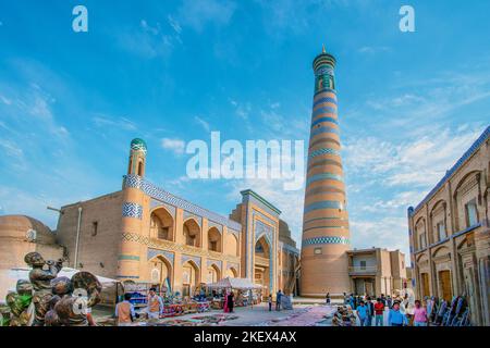 05-11-2022 Khiva Uzbekistan. Idilliaco vista sul minareto Islam-Khoja e bar camerieri e solo a piedi uzchi nella città vecchia di Khiva Foto Stock