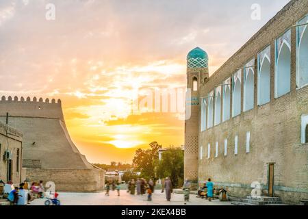 05-11-2022 Khiva , Uzbekistan. Tramonto nella città vecchia (medina) di Khiva - persone uzbeke a piedi. Fantastici minareti verdi. Foto Stock