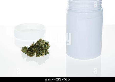 FLOS di cannabis, marijuana medica accanto al contenitore su sfondo bianco Foto Stock