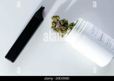 Cannabis flos, marijuana medica in contenitore bianco accanto al vaporizzatore, modo sicuro per prendere la medicina Foto Stock