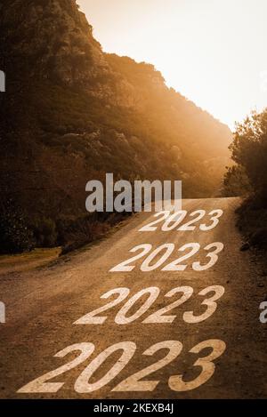 2023 scritto su strada forestale al tramonto. Concetto per il nuovo anno 2023. Foto Stock