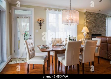 Tavolo in legno di quercia scuro con schienale alto bianco e sedie in legno nella sala da pranzo all'interno di una casa contemporanea in stile country. Foto Stock