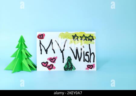 Natale lettera desiderio da capretto concetto. Primo piano di un disegno scritto accanto ad un albero di natale. Foto Stock