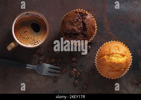 Due muffin e una tazza di caffè su uno sfondo di metallo grunge, vista dall'alto Foto Stock