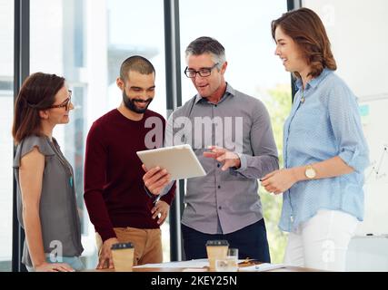 Con la tecnologia moderna imparerai qualcosa di nuovo ogni giorno. Un gruppo di uomini d'affari discute qualcosa su un tablet digitale. Foto Stock